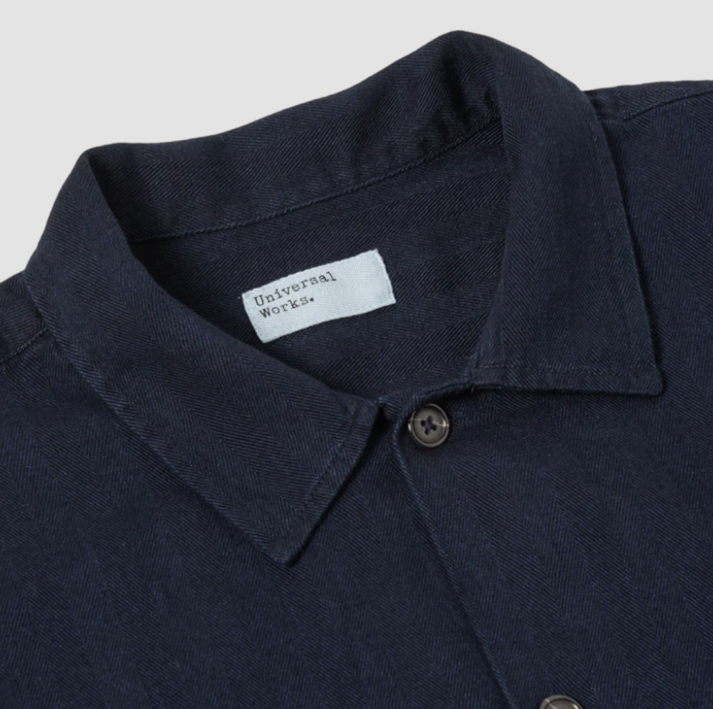 UW Herring Work Shirt: Oversized mid-century inspired shirt with herringbone fabric and button-closure pockets. Crafted from 100% cotton dyed with indigo.