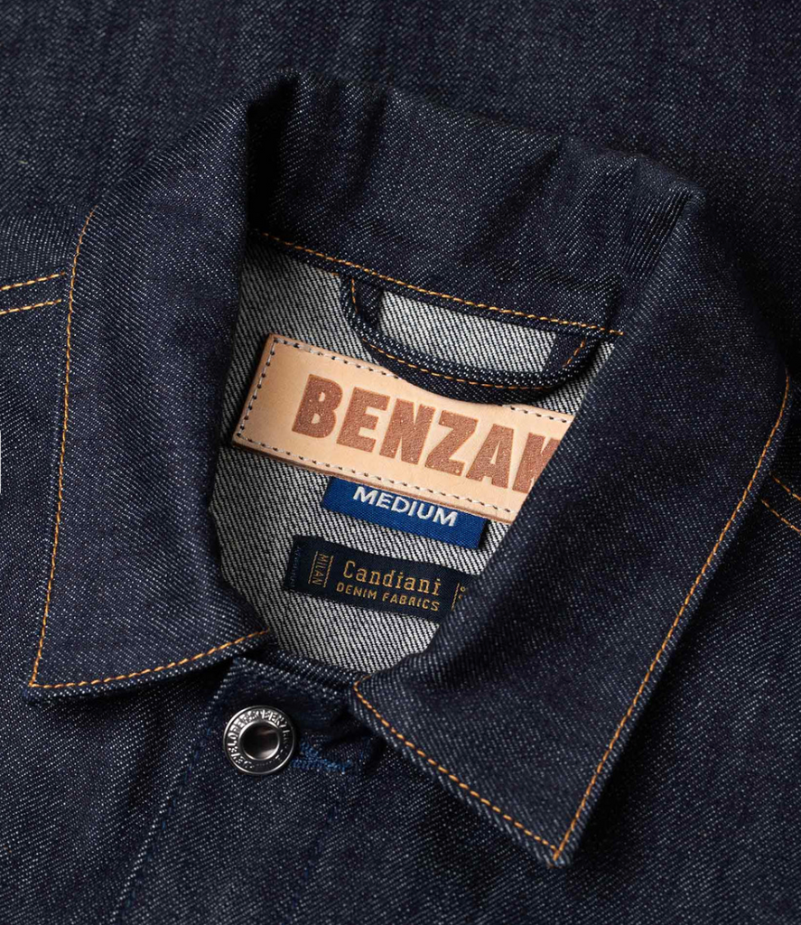 Slim-fit trucker jacket made from raw 15 oz. Italian selvedge denim with chest, hand-warmer, and inside pockets, showcasing vintage style.