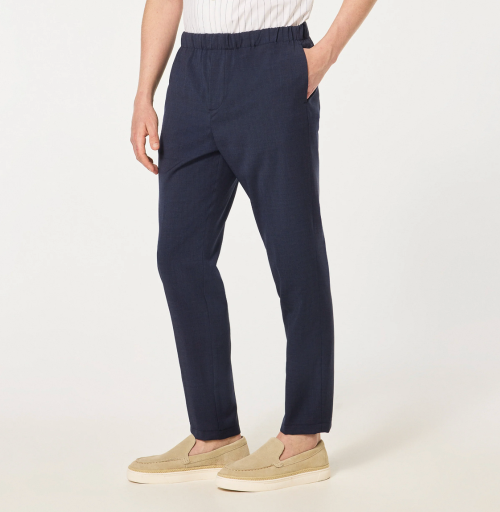 Cruna Burano pants in blue featuring a loose fit, elastic waistband, front and back flap pockets, and an embroidered Cruna logo on the right hip.