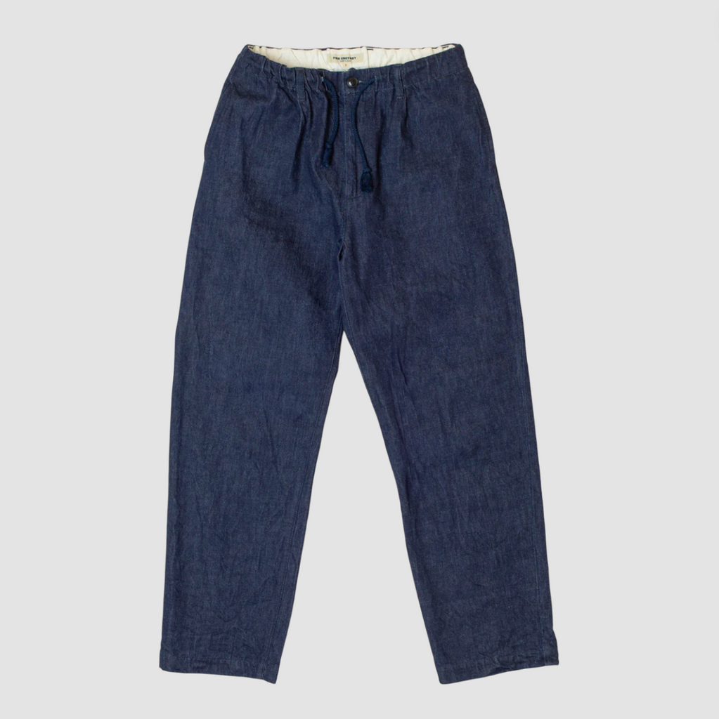 A pair of denim chinos on a light grey background. 