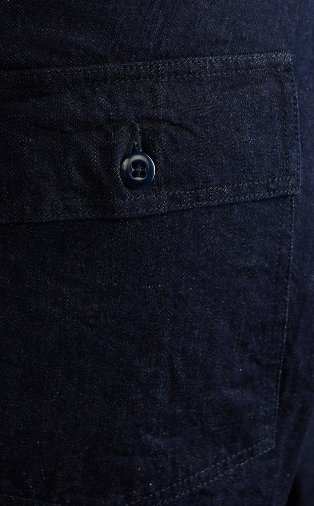 Close up of a pair of denim baker pants on light grey background. 