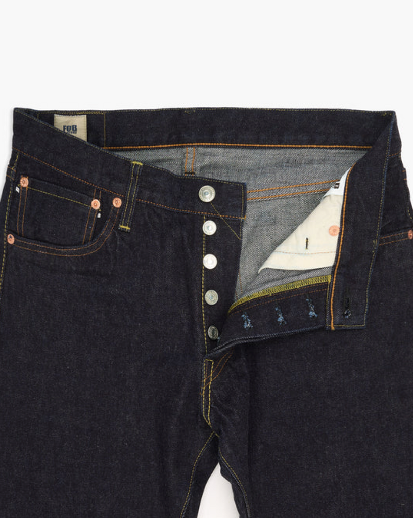 Close up of a pair of Japanese selvedge denim jeans on a light grey background.