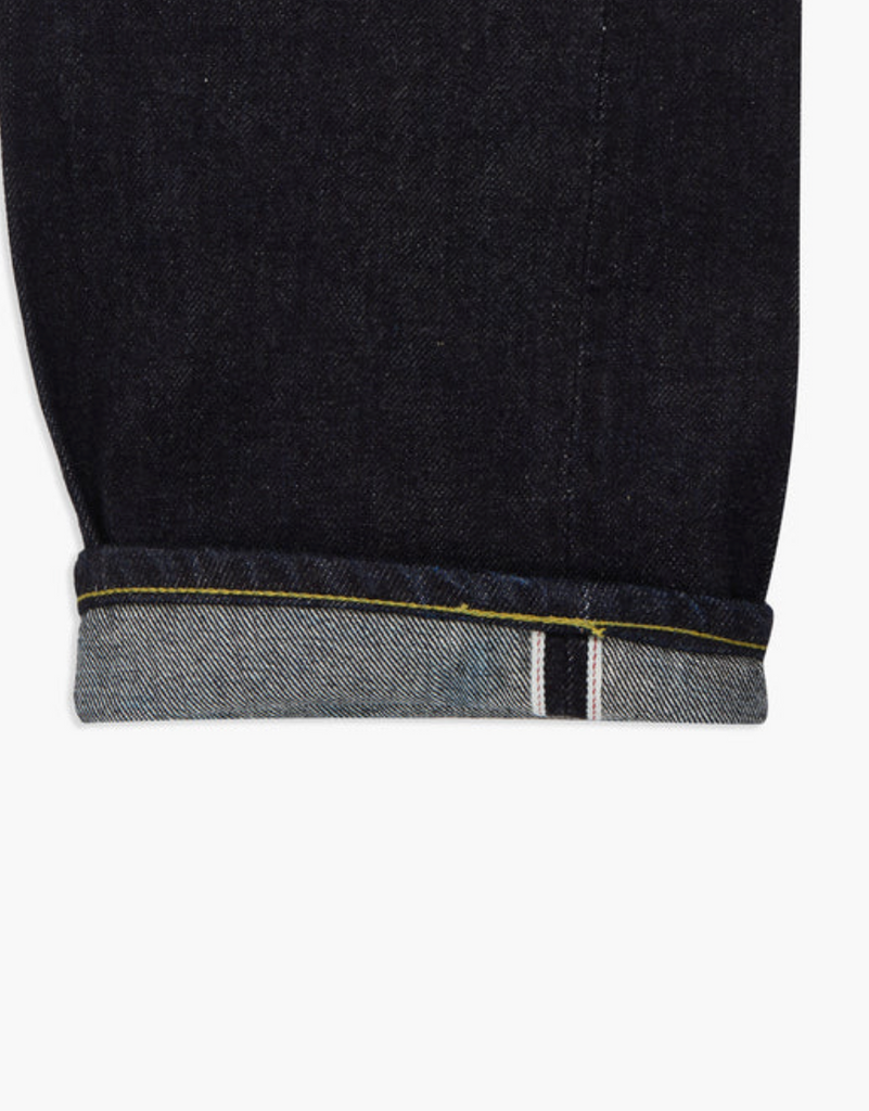 Close up of a pair of Japanese selvedge denim jeans on a light grey background.