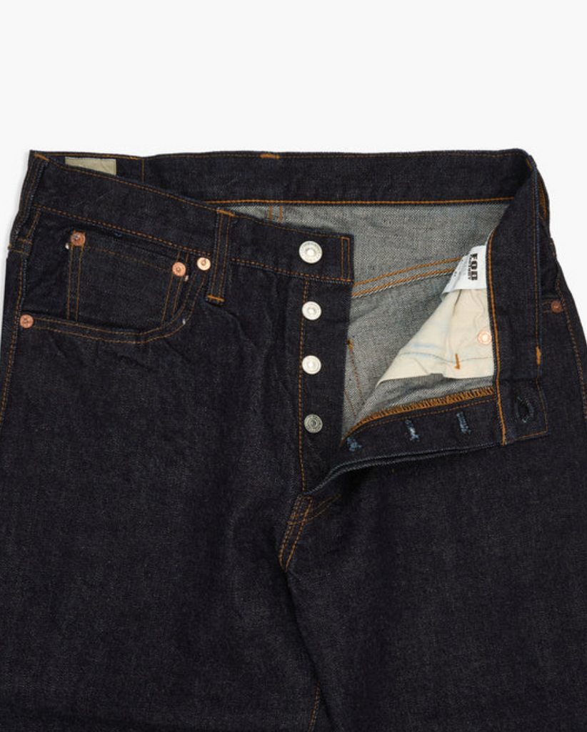 Close up of a pair of Japanese selvedge denim jeans on a light grey background.