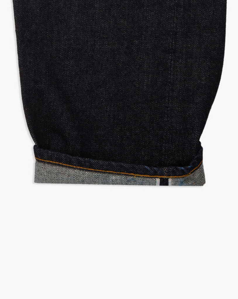 Close up of a pair of Japanese selvedge denim jeans on a light grey background.