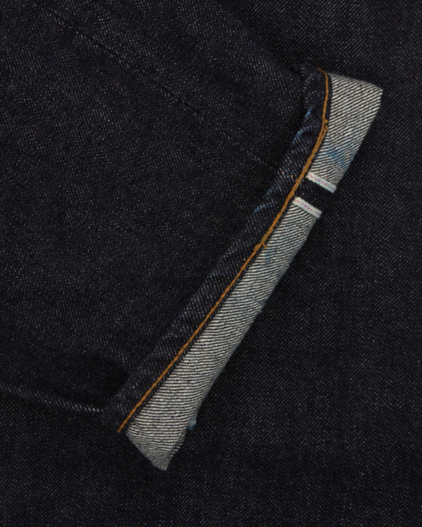Close up of a pair of Japanese selvedge denim jeans on a light grey background.