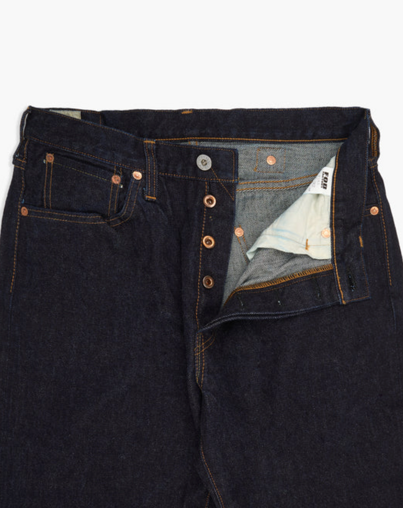 Close up of a pair of Japanese selvedge denim jeans on a light grey background.