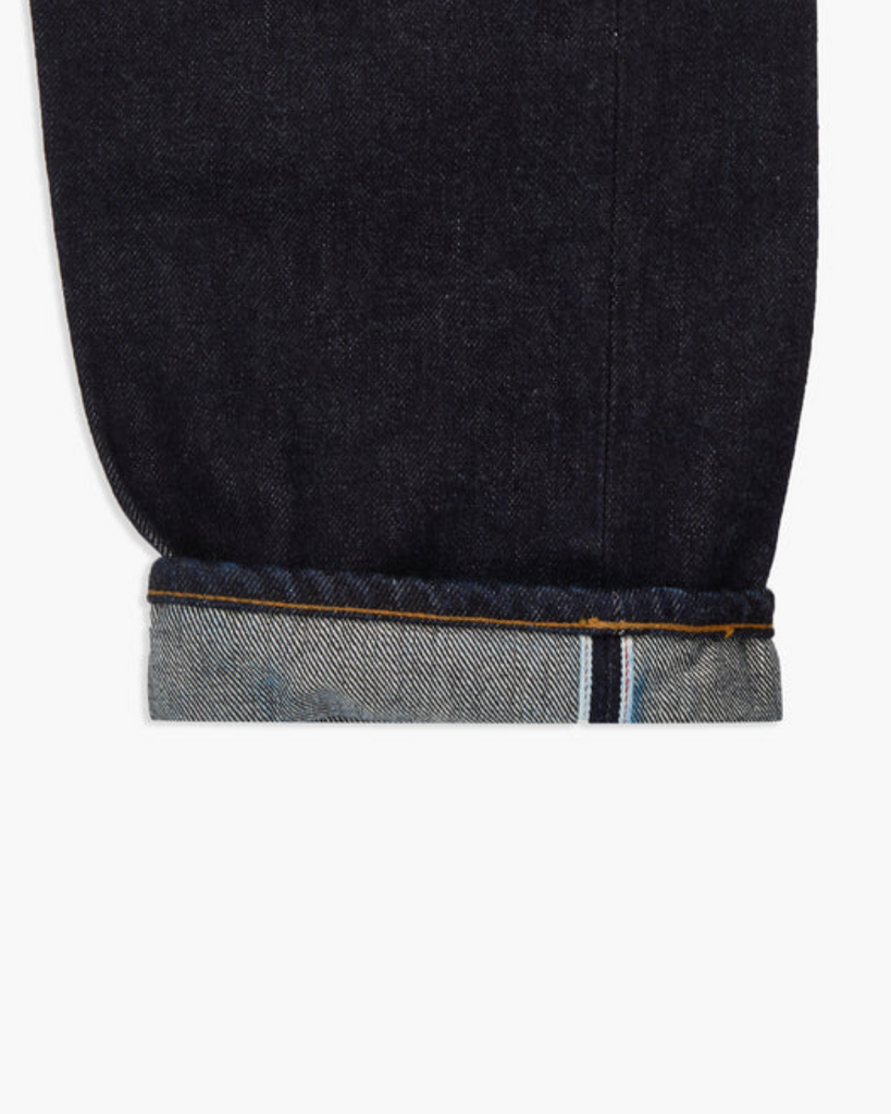 Close up of a pair of Japanese selvedge denim jeans on a light grey background.