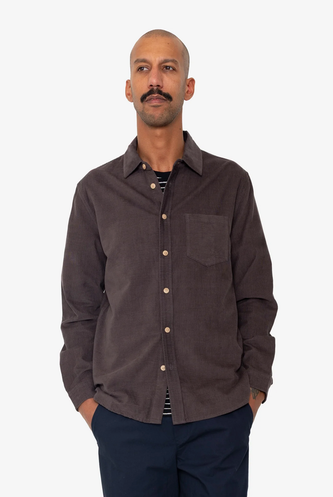 Man wearing a purple button-up shirt with a white background.