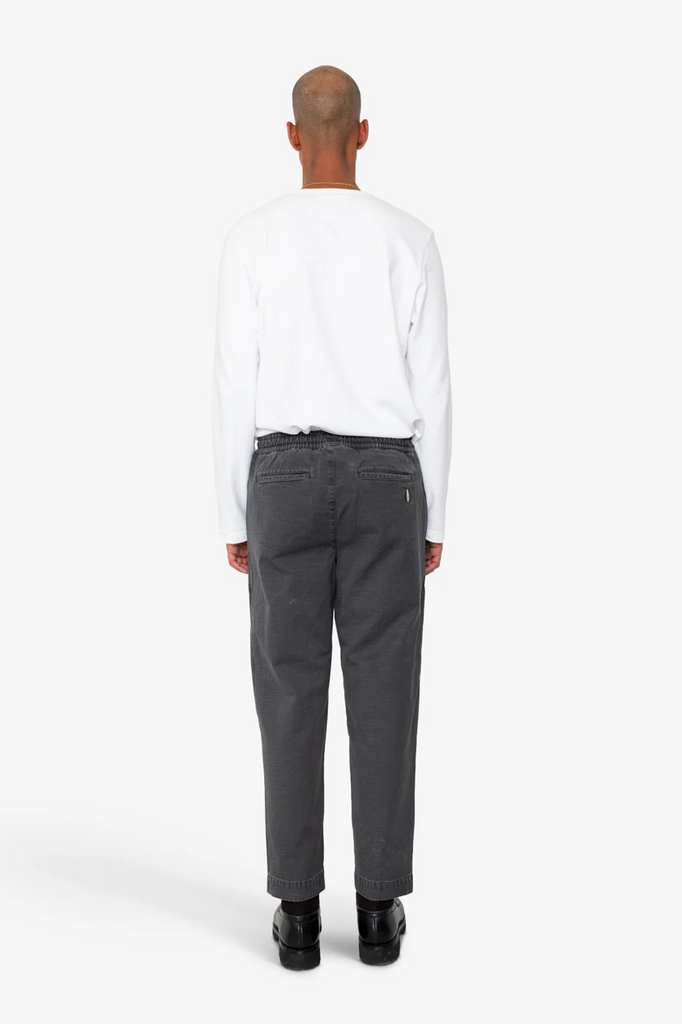 Person wearing a white shirt and gray pants on a white background.
