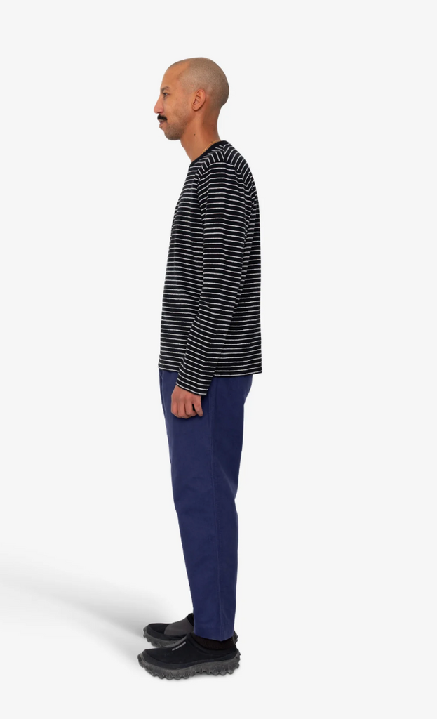 Man wearing a black and white striped shirt and blue pants on a white background.
