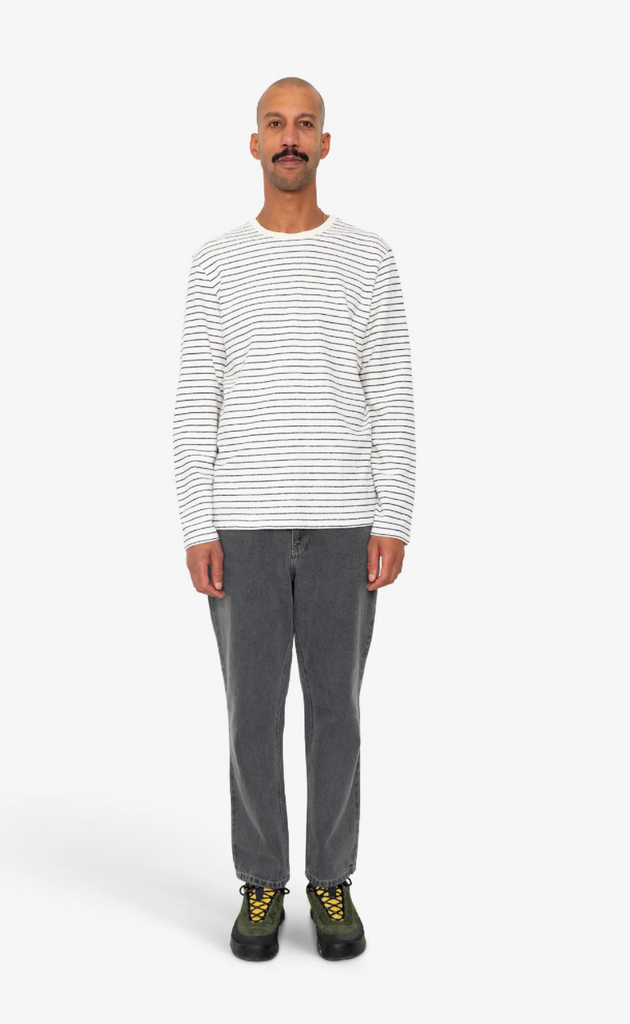 Man wearing a striped t-shirt and gray pants on a white background.