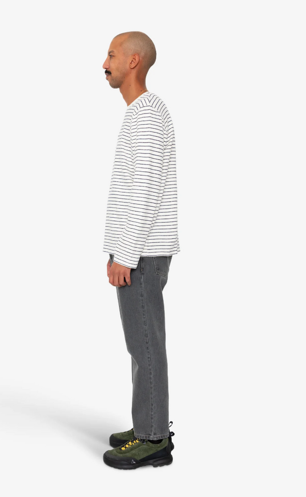 Person wearing a striped long-sleeve shirt and gray jeans on a white background.