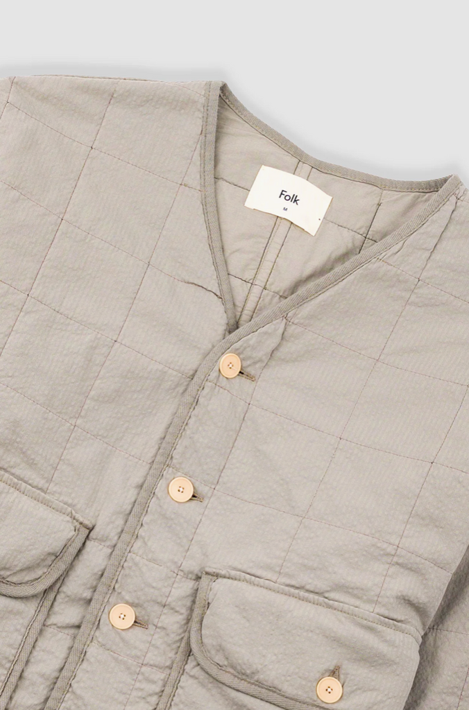Close up of a Grey quilted liner jacket on a grey background.