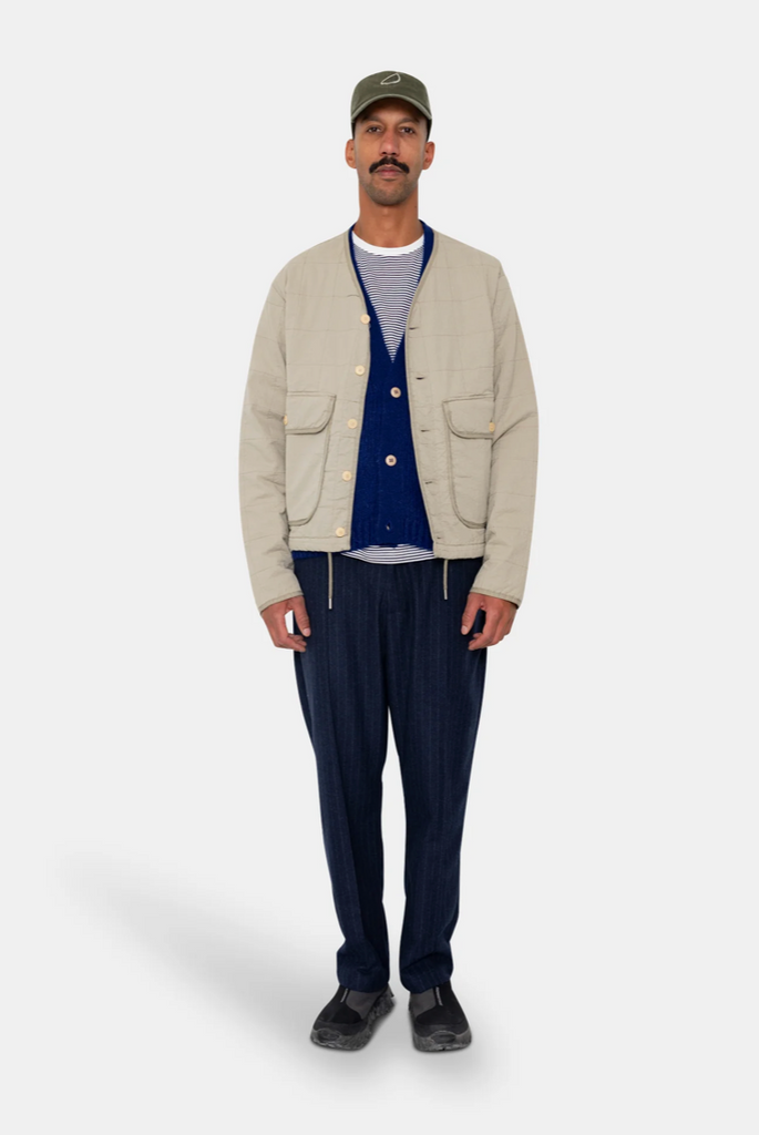 Man wearing a grey quilted liner jacket on a grey background.