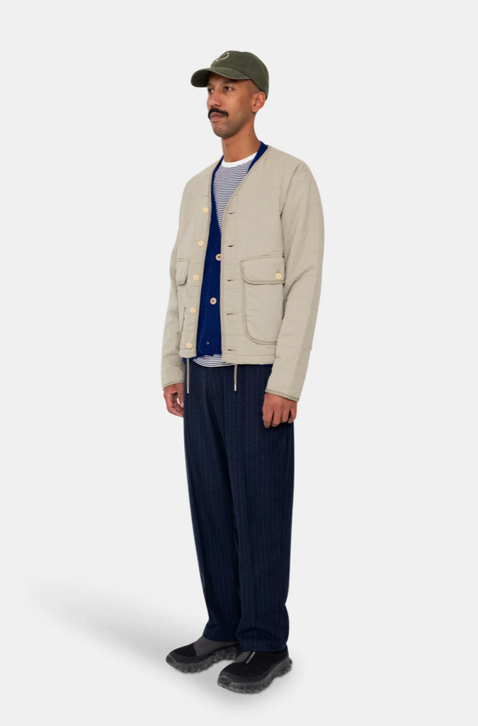 Man wearing a grey quilted liner jacket on a grey background.