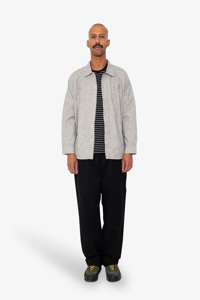 Man wearing a light Black and white stripe shirt and black pants on a white background.