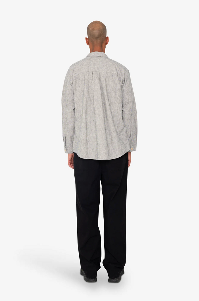 Person wearing a Black and white stripe shirt and black pants on a white background.