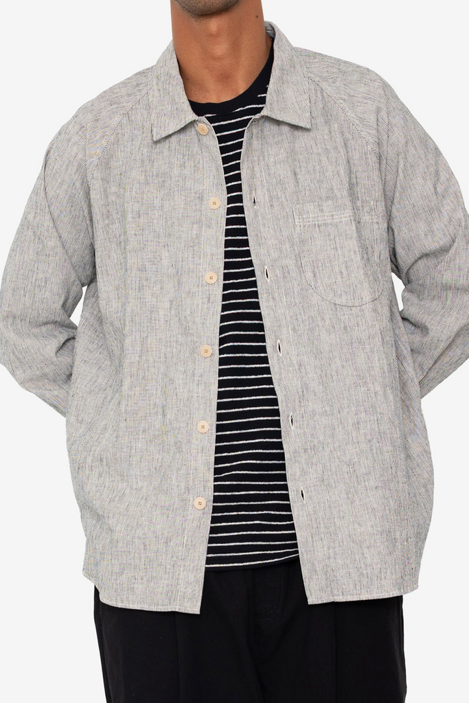 Person wearing a Black and white stripe shirt over a striped black and white tshirt on a white background.