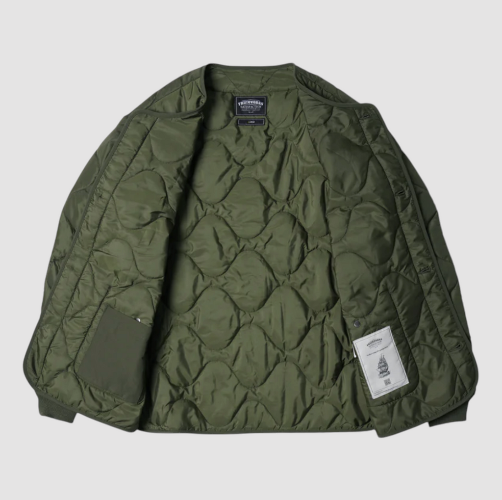 Olive green quilted field liner jacket with a cotton-nylon blend, lightweight down fill, and military-inspired buttons. Designed and made in Korea.
