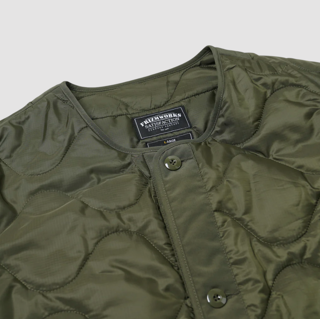 Olive green quilted field liner jacket with a cotton-nylon blend, lightweight down fill, and military-inspired buttons. Designed and made in Korea.