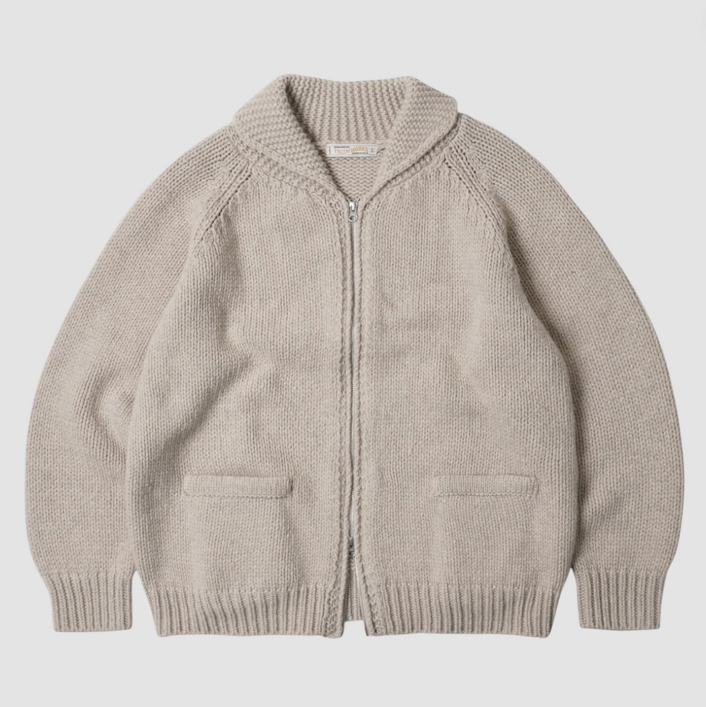Beige knitted cardigan with a zipper on a light gray background.