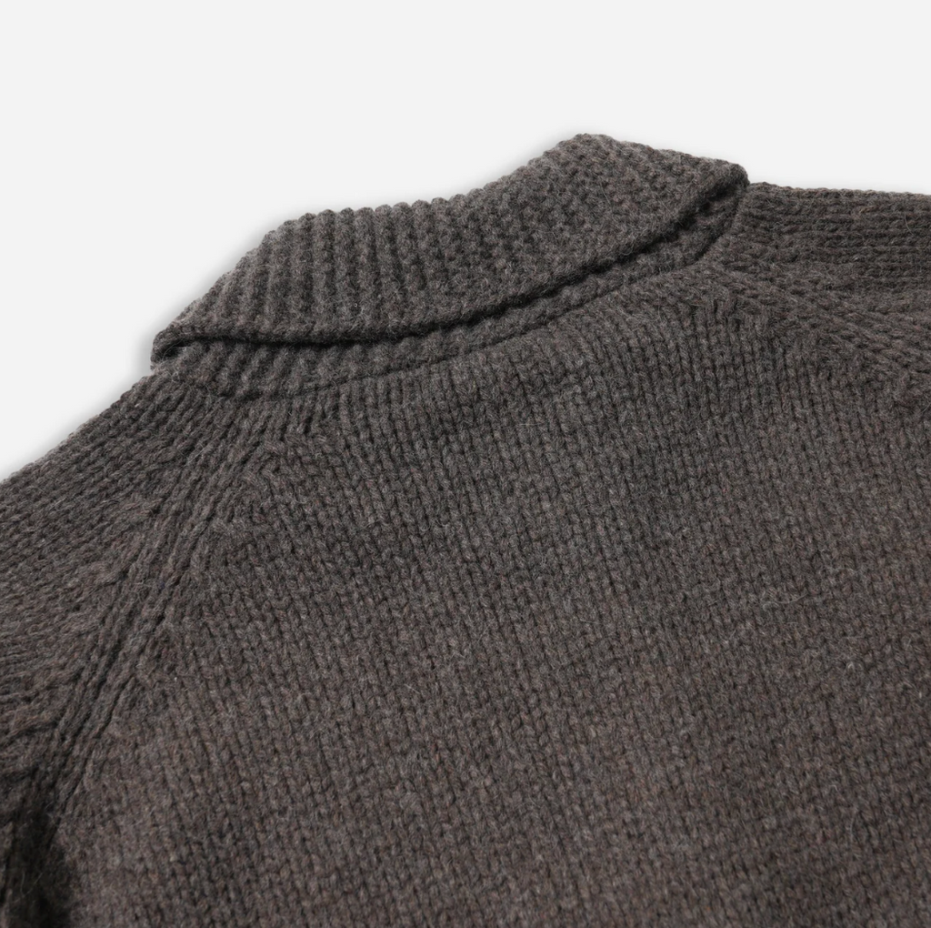 Close-up of a brown knitted sweater collar on a light gray background.