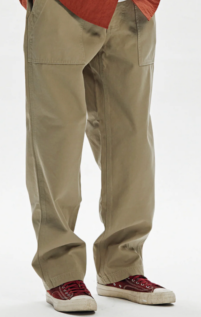 Beige pants worn with red shoes on a white background.