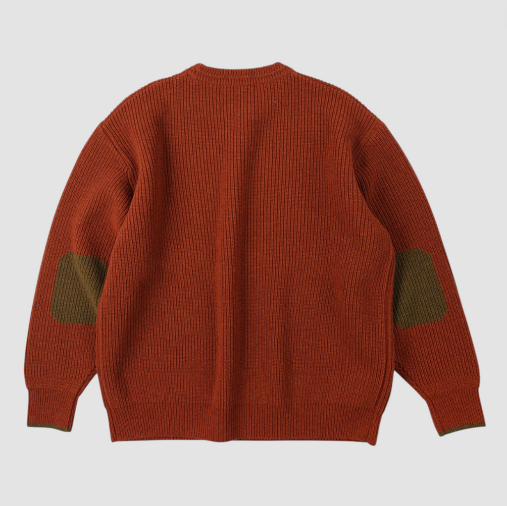 Orange sweater with green elbow patches on a light gray background.