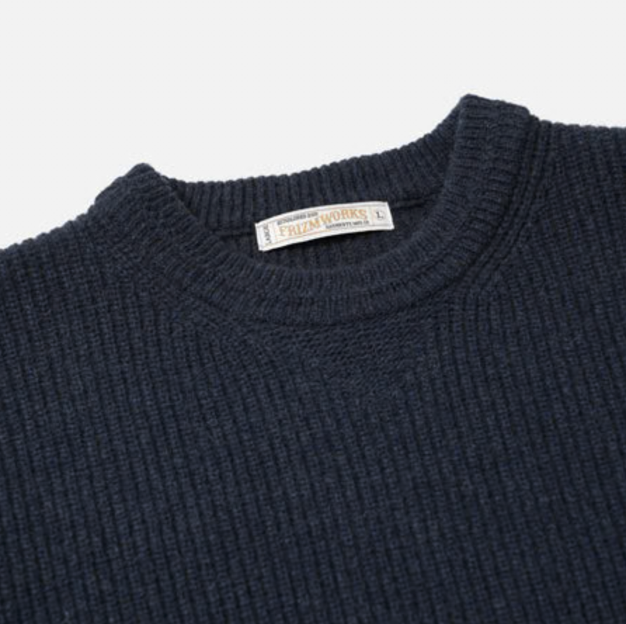 Navy blue sweater with a brand label on a light gray background.