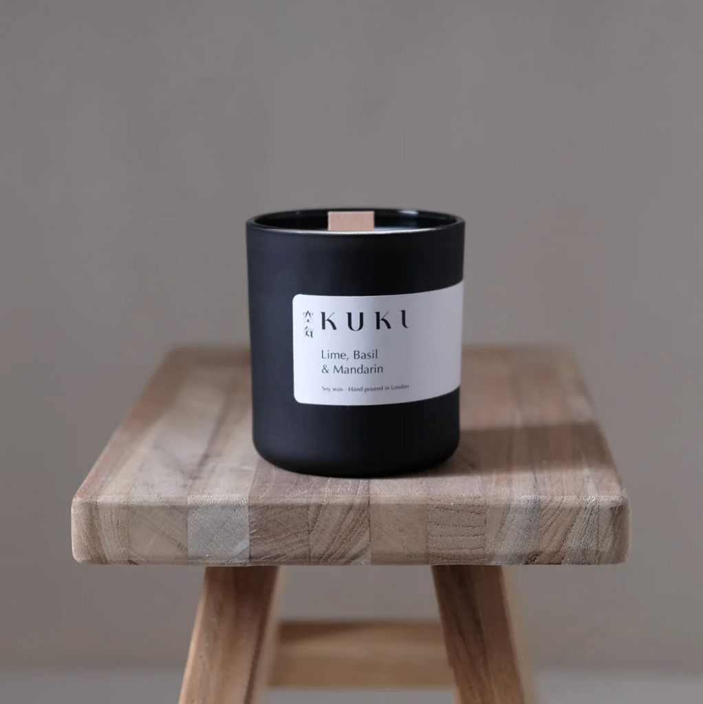 Hand-poured candle with Sicilian lime, basil, and mandarin fragrance in a matte black jar, featuring a wooden wick and 50-hour burn time.