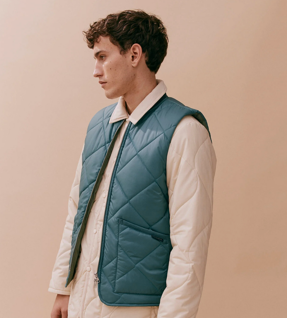 Quilted bomber gilet in Tapestry Blue with a two-way zip, ribbed collar, and two patch pockets, made with lightweight yet warm wadding.