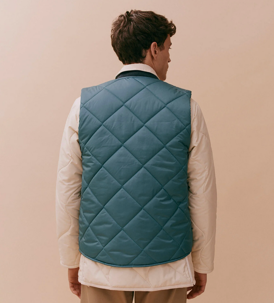 Quilted bomber gilet in Tapestry Blue with a two-way zip, ribbed collar, and two patch pockets, made with lightweight yet warm wadding.