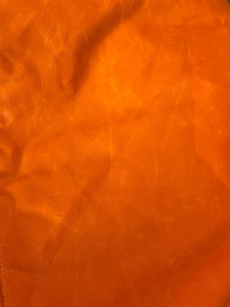 Close up of orange wax jacket fabric.