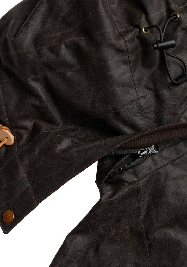 Close up of a brown wax jacket with hood on a light grey background.