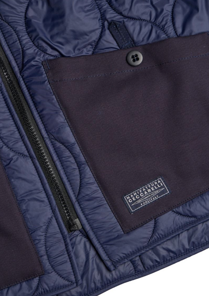 Close up of a navy zip-up liner jacket on a light grey background.