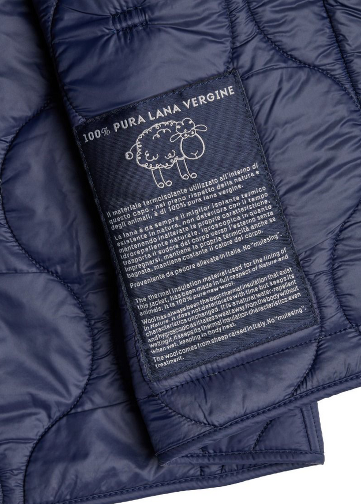 Close up of a navy zip-up liner jacket on a light grey background.