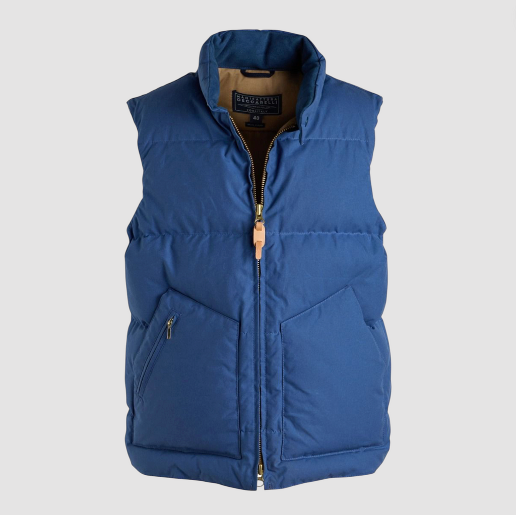 Blue puffer vest with zip fastenings on a light grey background. 