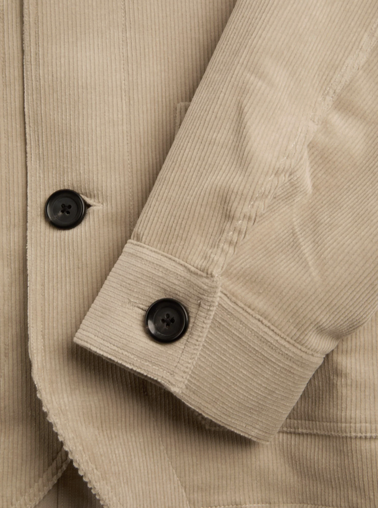 Close-up of a beige corduroy jacket with black buttons.