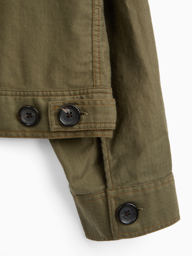 A green trucker jacket in a linen-cotton herringbone blend, featuring button fastening, welted pockets, and a chest patch pocket for a classic look.