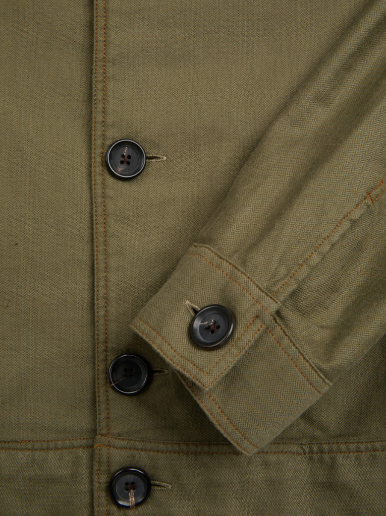 A green trucker jacket in a linen-cotton herringbone blend, featuring button fastening, welted pockets, and a chest patch pocket for a classic look.