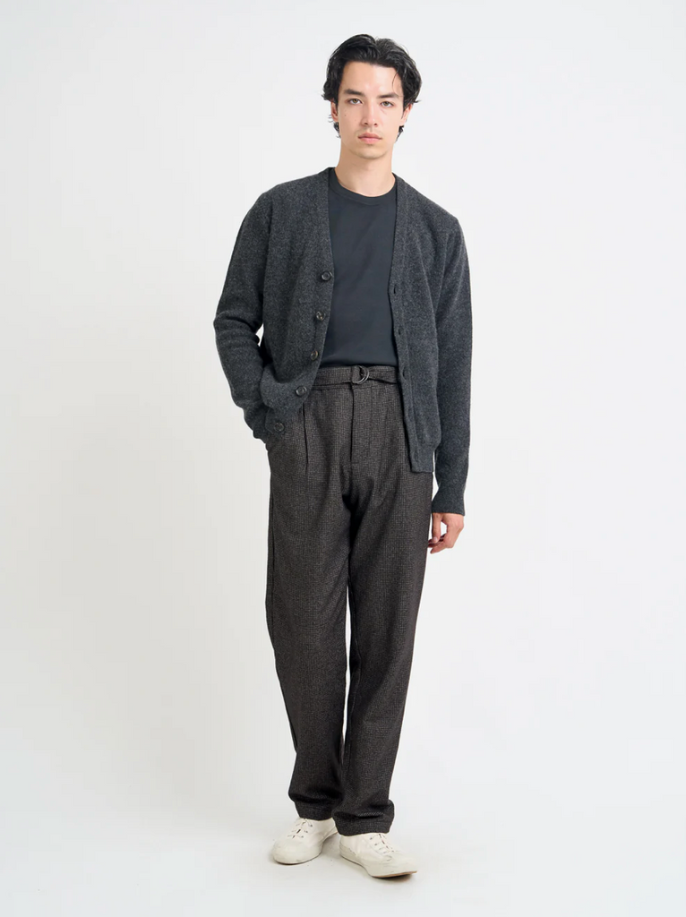 Man wearing a gray cardigan, dark shirt, and pants on a white background.
