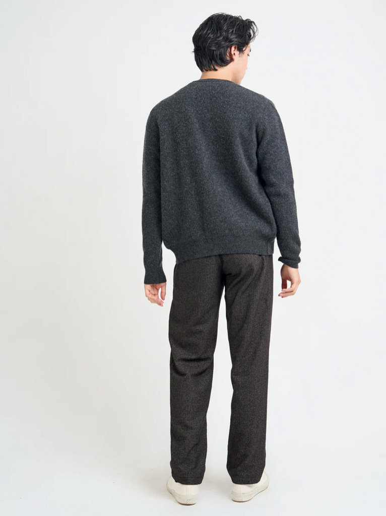 Person wearing a dark gray cardigan and pants on a white background.