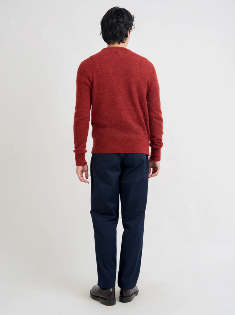 Person wearing a red sweater and navy pants on a white background.