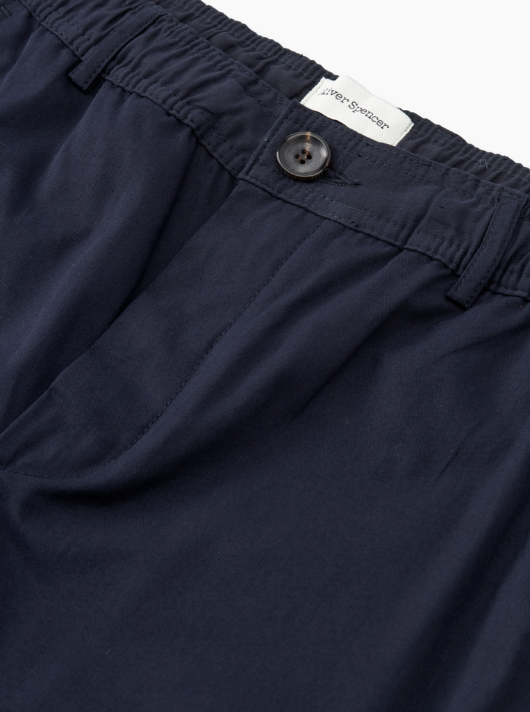 Navy blue pants with a button and label on a white background.