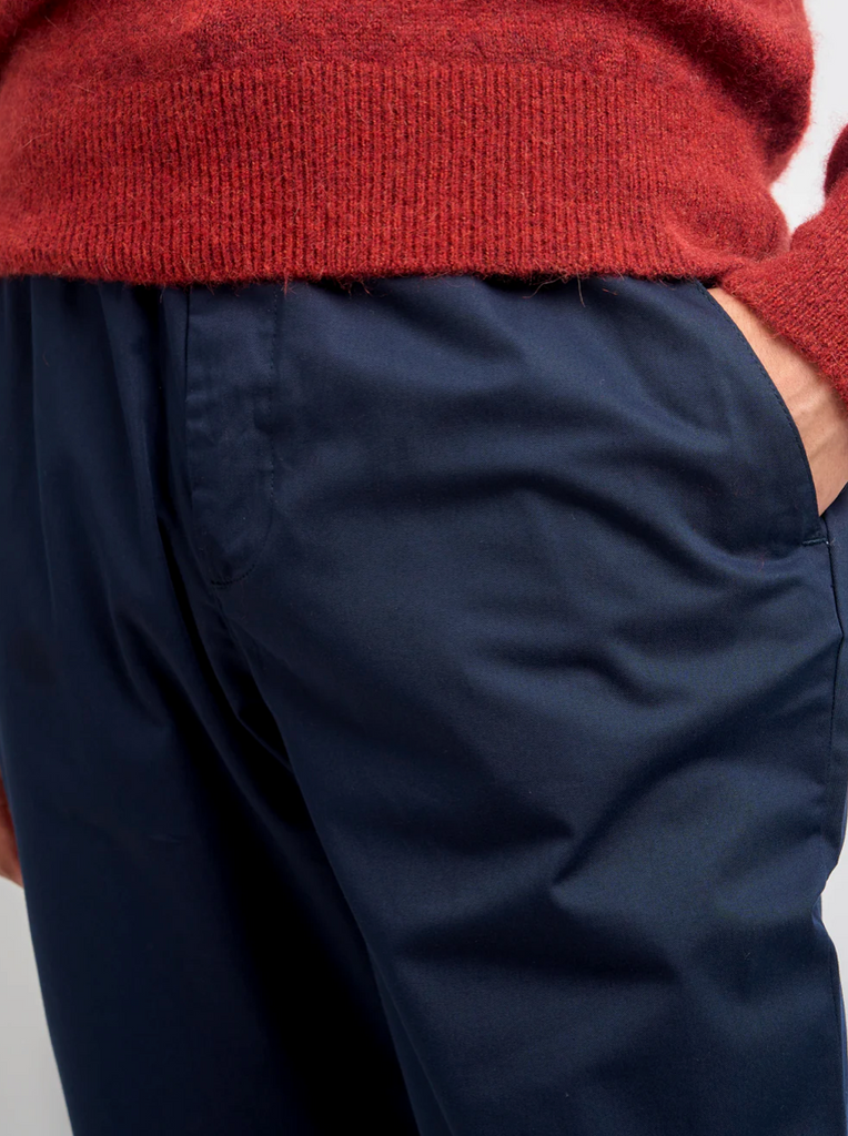 Navy pants worn with a red sweater on a light gray background.