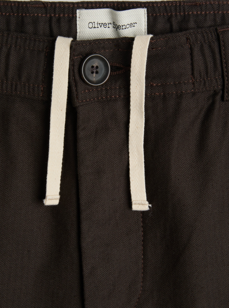 A pair of brown drawstring trousers with a straight-leg cut, crafted from a cotton-linen herringbone blend, featuring a button fly and rear pockets.