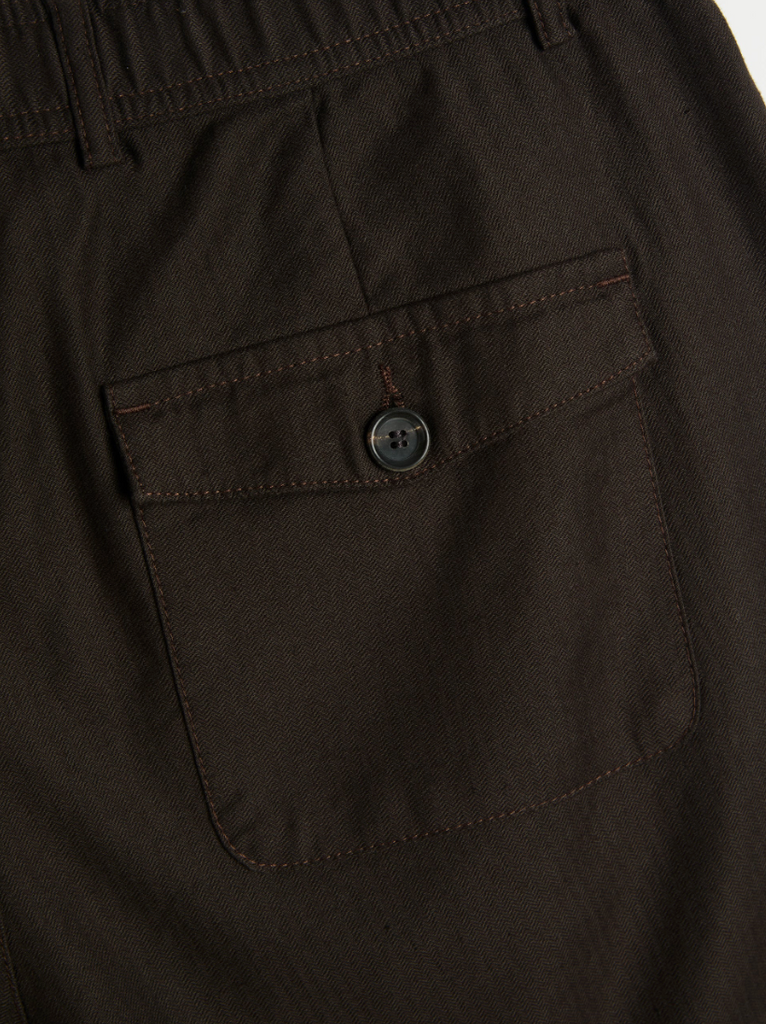 A pair of brown drawstring trousers with a straight-leg cut, crafted from a cotton-linen herringbone blend, featuring a button fly and rear pockets.