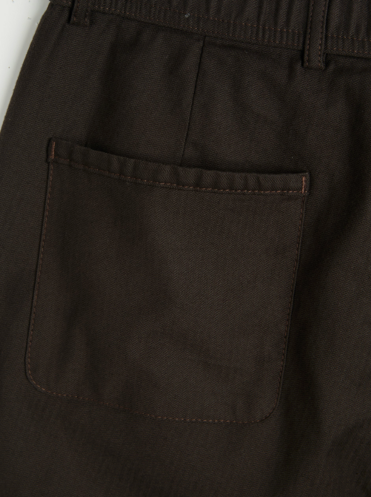 A pair of brown drawstring trousers with a straight-leg cut, crafted from a cotton-linen herringbone blend, featuring a button fly and rear pockets.