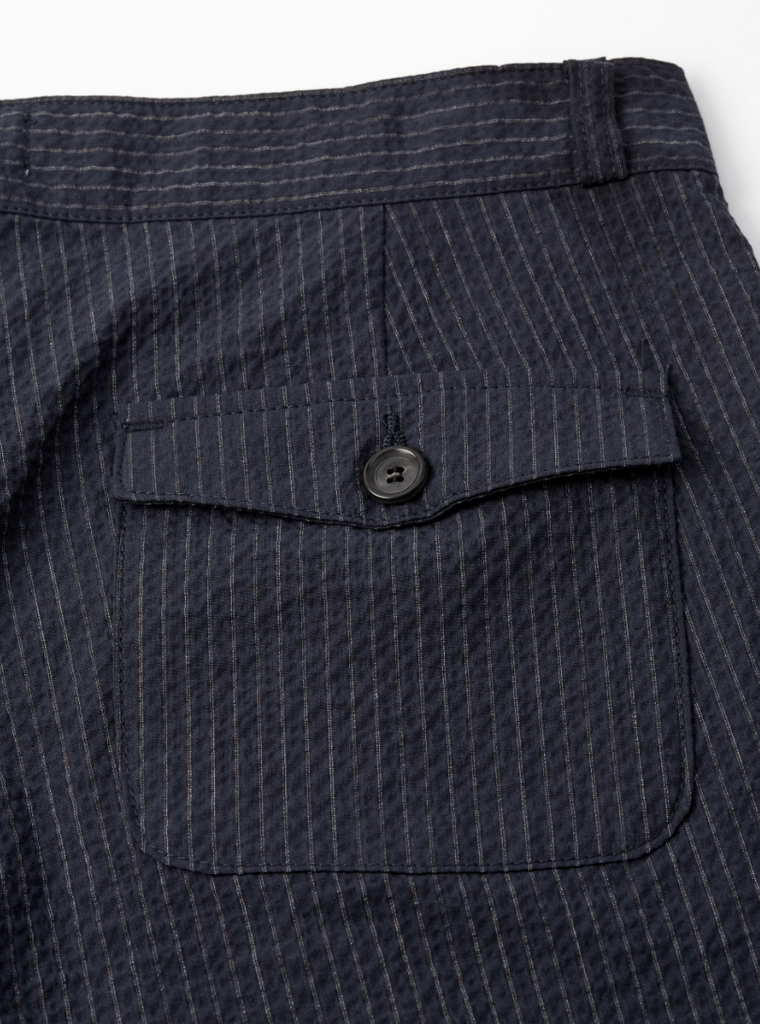 A pair of navy pleated trousers with a straight-leg cut, crafted from soft stretch cotton denim with front and rear pockets.